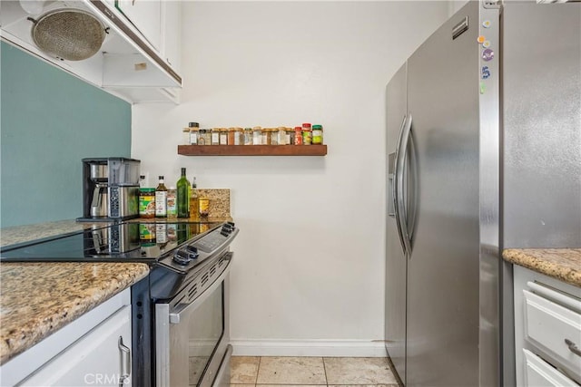 kitchen with light tile patterned flooring, light stone countertops, white cabinets, and stainless steel appliances