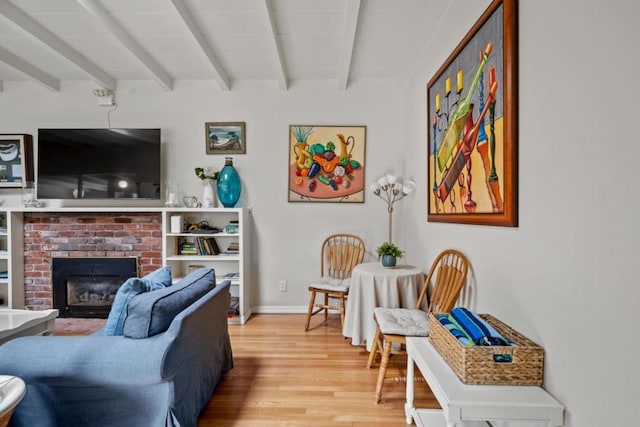 living room with hardwood / wood-style floors, a fireplace, and beamed ceiling