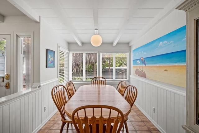 dining area featuring wood walls, beamed ceiling, and light tile patterned floors