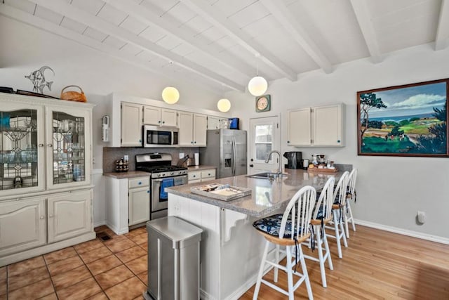 kitchen featuring white cabinetry, sink, stainless steel appliances, a kitchen bar, and light wood-type flooring