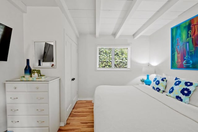 bedroom featuring beamed ceiling and light hardwood / wood-style floors