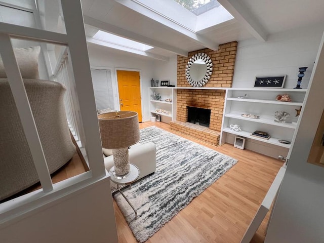 living room with lofted ceiling with beams, wood-type flooring, and a brick fireplace