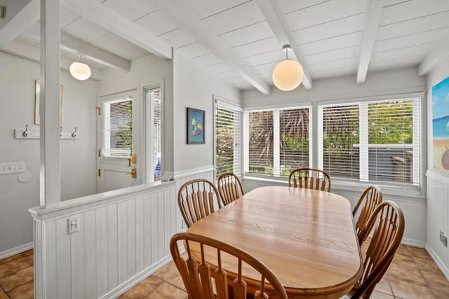 tiled dining space featuring beamed ceiling