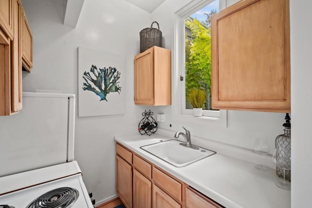 interior space featuring white stove, light brown cabinets, and sink