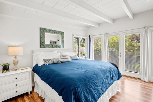 bedroom featuring beamed ceiling, hardwood / wood-style floors, and access to exterior