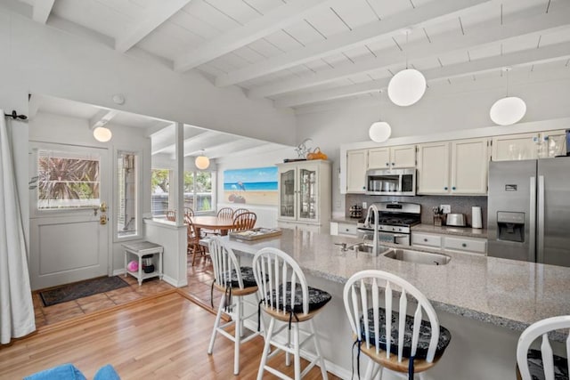 kitchen with light hardwood / wood-style floors, white cabinetry, pendant lighting, and appliances with stainless steel finishes