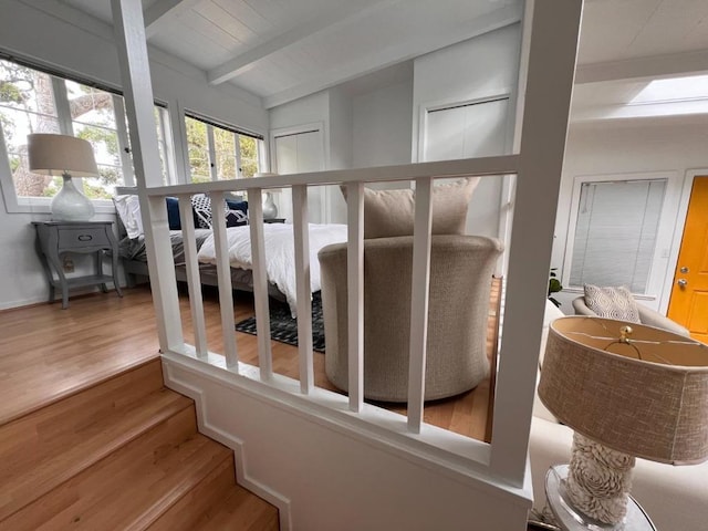 stairway featuring wood-type flooring and vaulted ceiling with beams