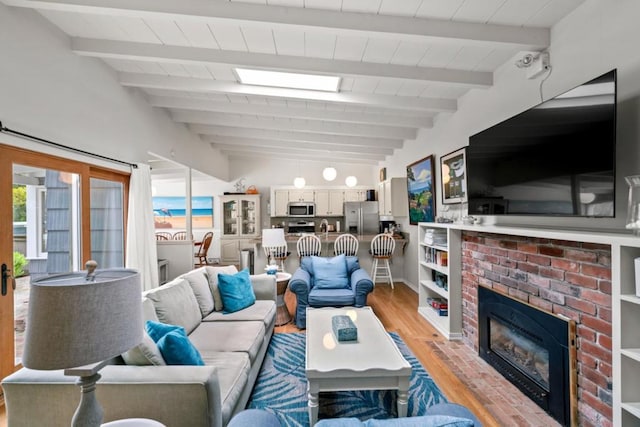 living room with lofted ceiling with beams, a fireplace, and light hardwood / wood-style flooring