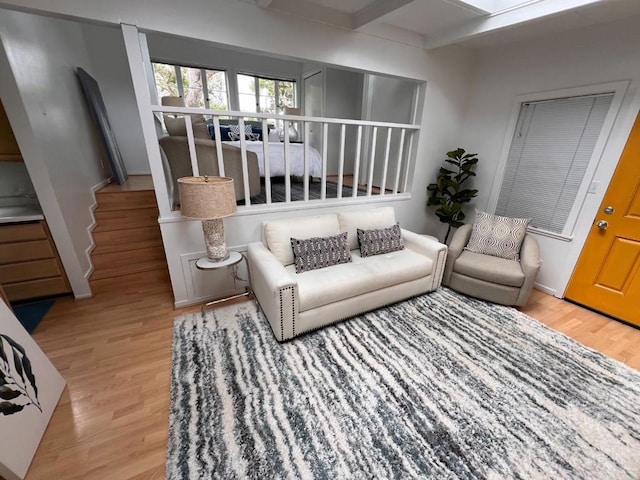 living room featuring beam ceiling and light hardwood / wood-style flooring