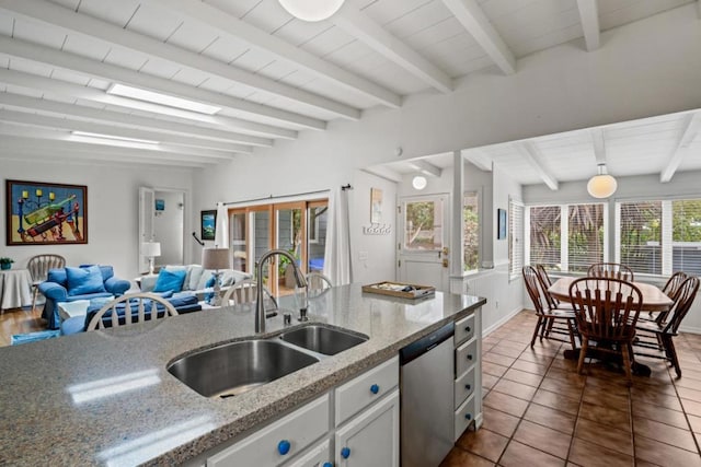 kitchen featuring sink, stainless steel dishwasher, light stone countertops, beamed ceiling, and white cabinetry