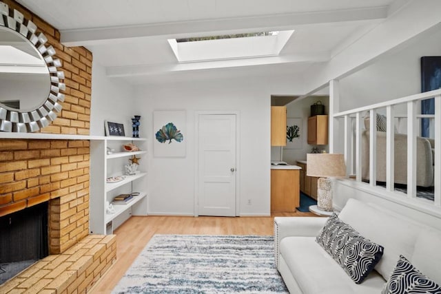 sitting room with beam ceiling, a fireplace, light hardwood / wood-style flooring, and a skylight