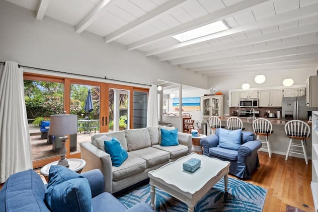 living room featuring light hardwood / wood-style floors, a skylight, beam ceiling, and french doors