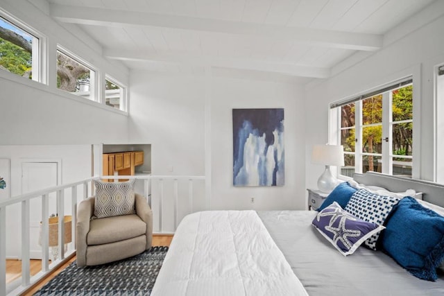 bedroom featuring hardwood / wood-style floors, vaulted ceiling with beams, and multiple windows