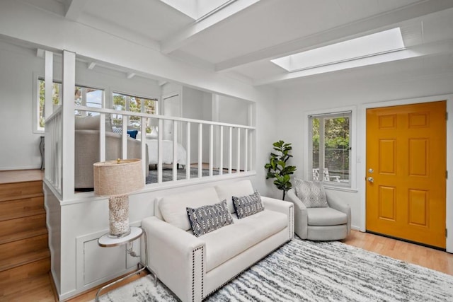 living room with hardwood / wood-style floors, beam ceiling, and a skylight