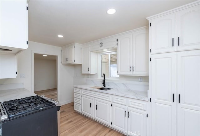 kitchen featuring white cabinets, black range oven, and sink