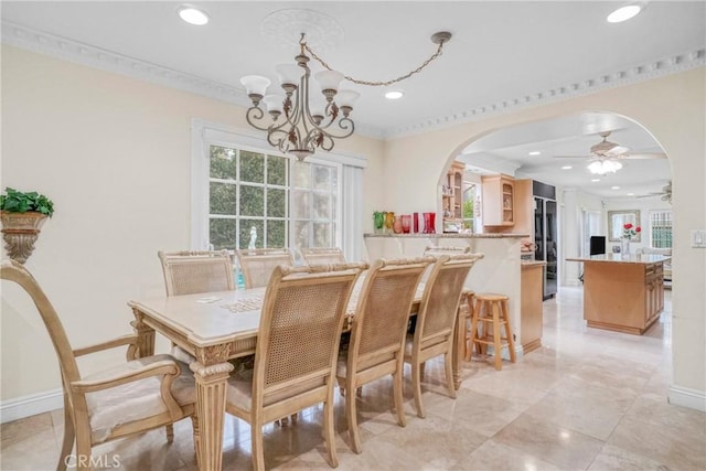 dining space with ceiling fan with notable chandelier and ornamental molding