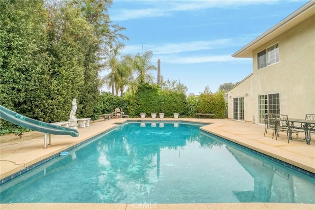 view of pool featuring a water slide and a patio