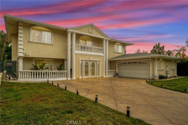 view of front of property featuring french doors, a yard, a balcony, and a garage