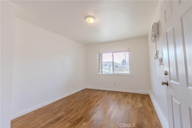 unfurnished room with an AC wall unit and hardwood / wood-style flooring