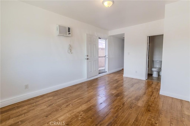 empty room featuring hardwood / wood-style flooring and an AC wall unit