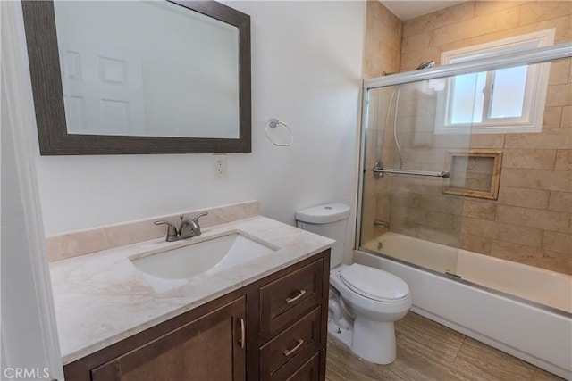 full bathroom with vanity, bath / shower combo with glass door, and toilet