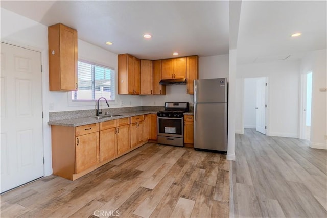 kitchen featuring light stone countertops, appliances with stainless steel finishes, light wood-type flooring, and sink