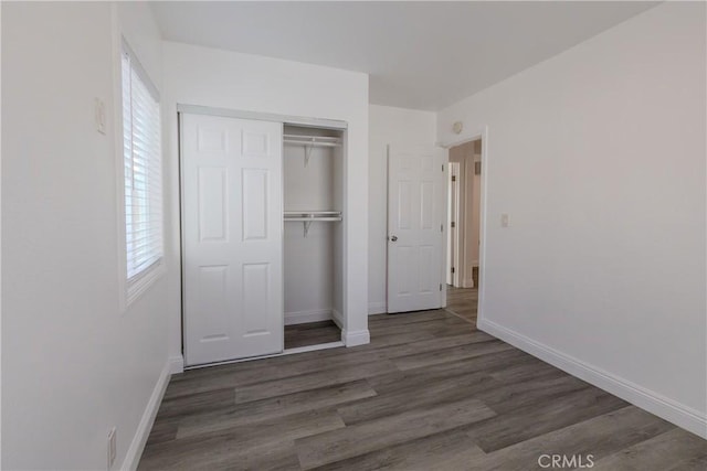 unfurnished bedroom with a closet, dark hardwood / wood-style floors, and multiple windows