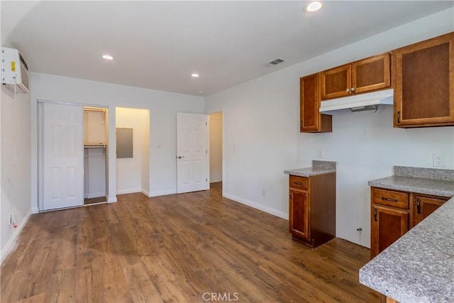 kitchen featuring a wall unit AC and dark hardwood / wood-style floors