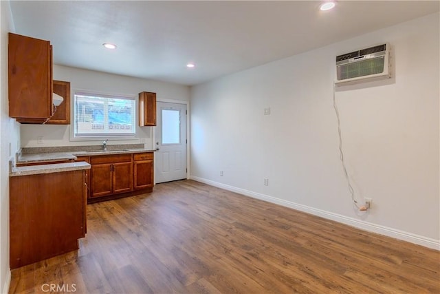 kitchen with hardwood / wood-style flooring, sink, and a wall unit AC