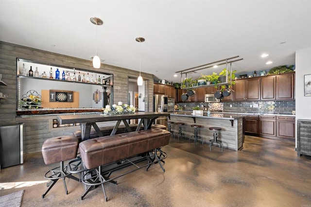 bar featuring appliances with stainless steel finishes, decorative light fixtures, tasteful backsplash, and wooden walls