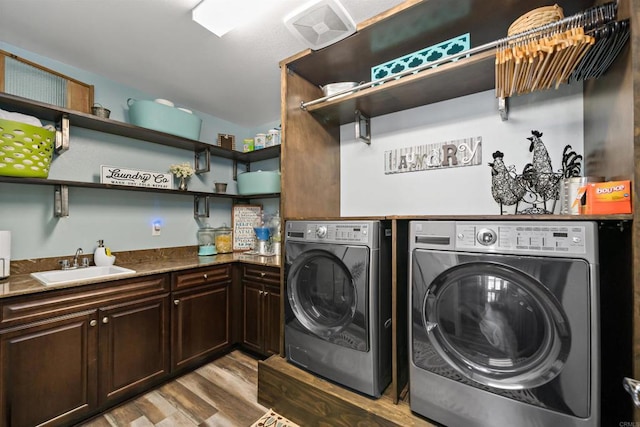 washroom with cabinets, washer and dryer, sink, and light hardwood / wood-style flooring