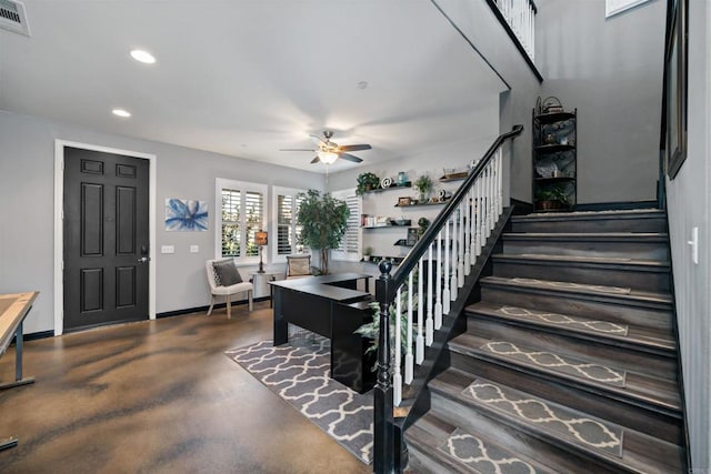 stairs featuring ceiling fan and concrete flooring