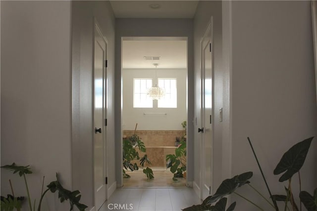 hall featuring light tile patterned flooring and an inviting chandelier