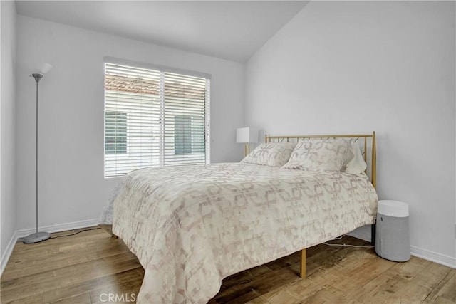 bedroom with wood-type flooring and vaulted ceiling