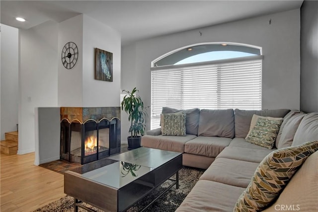 living room with a tiled fireplace and wood-type flooring