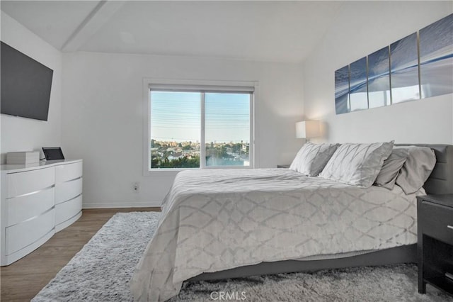 bedroom featuring a water view, wood-type flooring, and vaulted ceiling