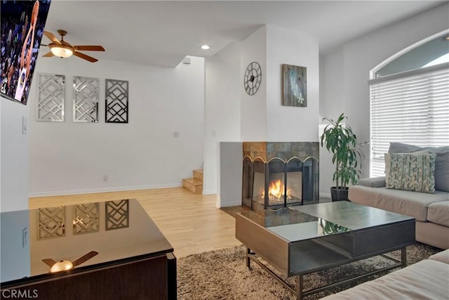 living room featuring ceiling fan, a fireplace, and light hardwood / wood-style floors