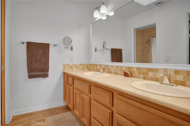 bathroom with tasteful backsplash, vanity, a shower, and wood-type flooring