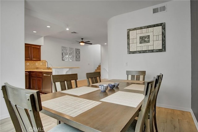 dining room with ceiling fan, sink, and light hardwood / wood-style flooring