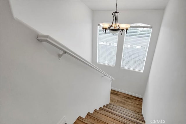 stairway with a notable chandelier and wood-type flooring