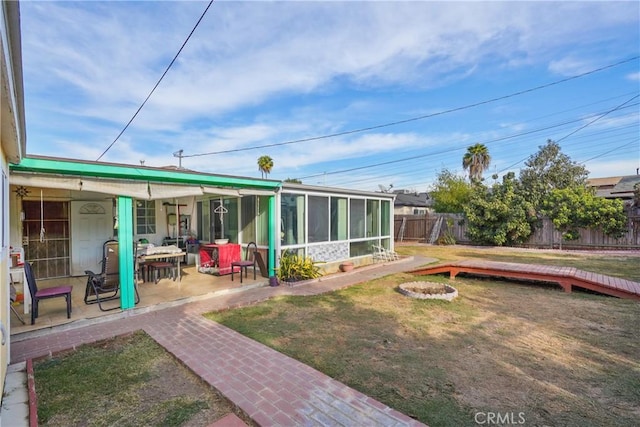 back of house featuring a sunroom, a patio area, a deck, and a yard