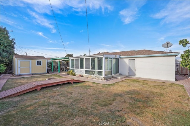 rear view of property featuring a yard, a sunroom, a storage shed, and a wooden deck