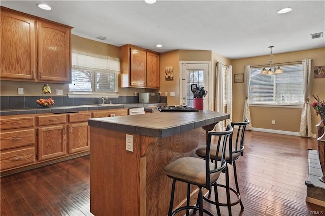 kitchen featuring decorative light fixtures, a kitchen island, dark hardwood / wood-style flooring, and a chandelier