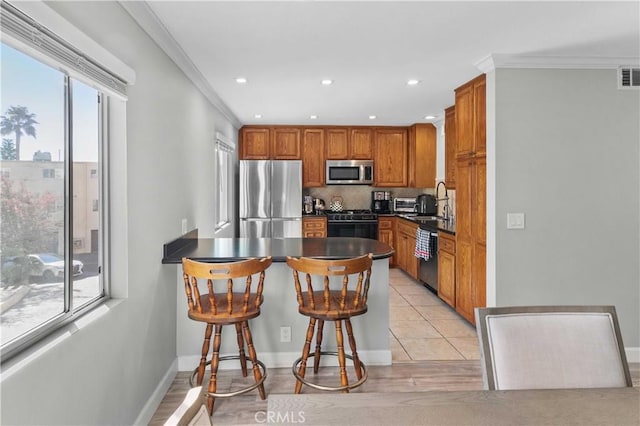 kitchen featuring plenty of natural light, ornamental molding, backsplash, and appliances with stainless steel finishes