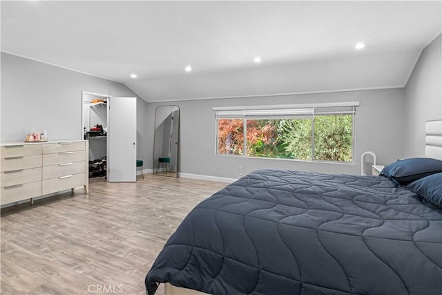 bedroom with lofted ceiling, a closet, a spacious closet, and light hardwood / wood-style flooring