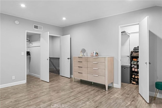 bedroom with light hardwood / wood-style floors, a walk in closet, and a closet