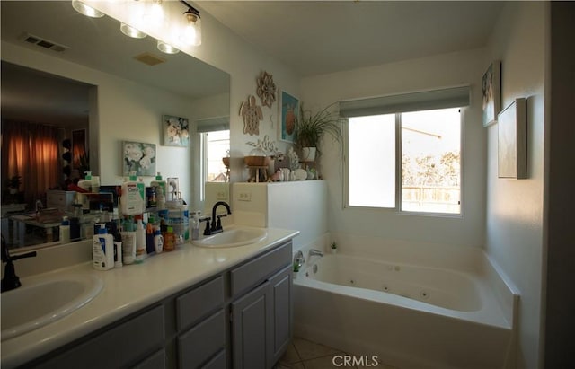 bathroom with a washtub, vanity, a healthy amount of sunlight, and tile patterned flooring