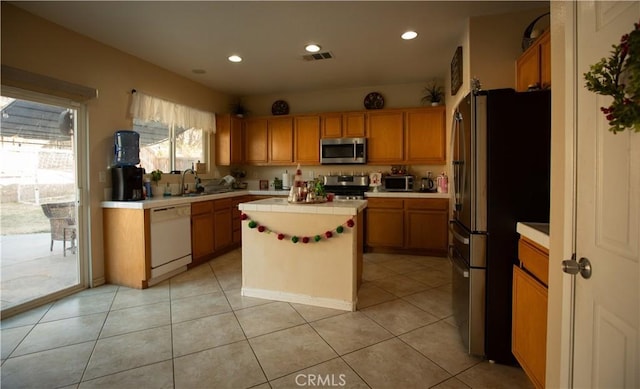 kitchen with appliances with stainless steel finishes, a center island, light tile patterned floors, and sink