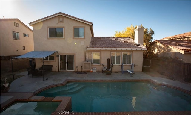 rear view of property featuring a fenced in pool and a patio