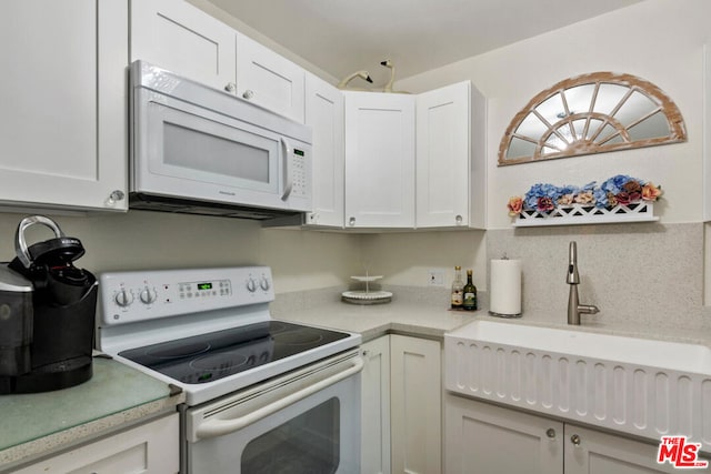 kitchen featuring white appliances, white cabinetry, and sink